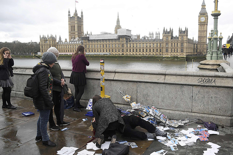 Un grupo de viandantes asiste a una de las víctimas, tendida en el suelo en mitad del famoso puente londinense. / REUTERS
