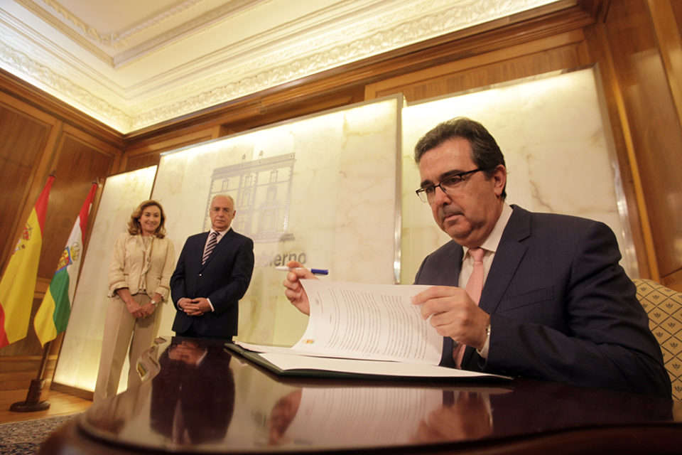 El vicepresidente de la Fundación Amancio Ortega, José Arnau, firma el protocolo, en presencia de José Ignacio Ceniceros, y María Martín, consejera de Salud. /ingrid