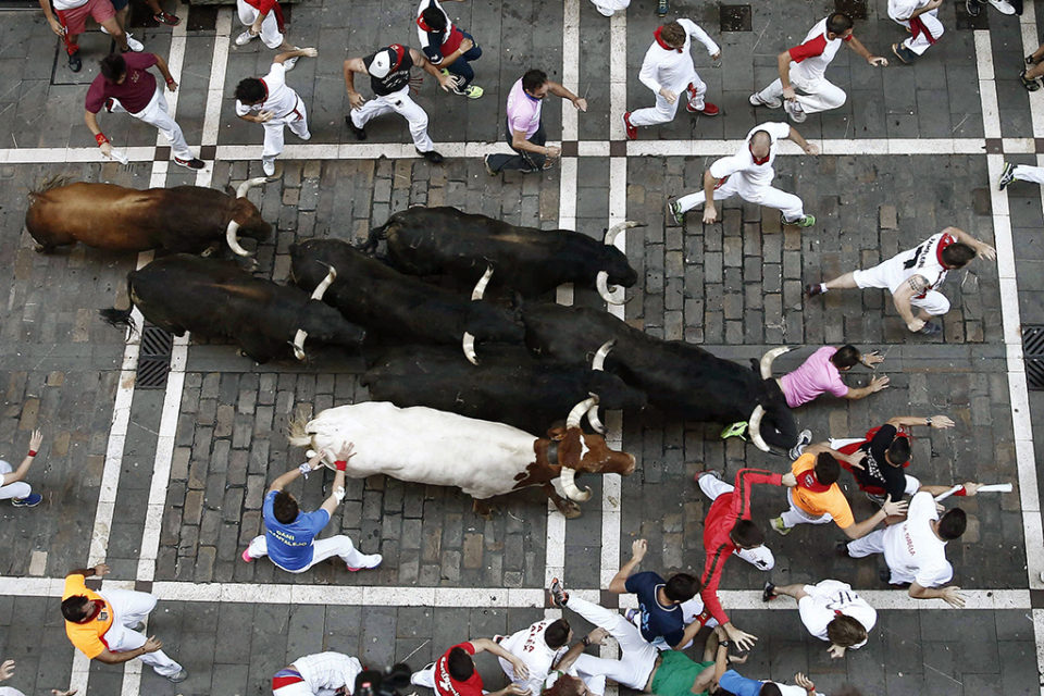 Los toros de la Ganadería de Victoriano cogen a un mozo a su paso por la calle Estafeta. / Jesús Diges ( Efe)
