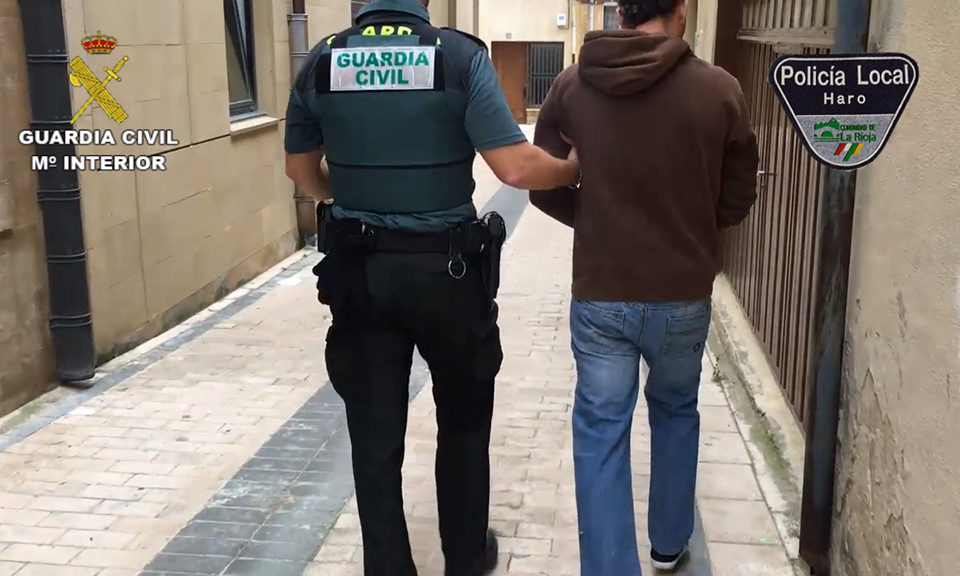 Un agente de la Guardia Civil conduce al detenido tras registrar el inmueble. / Guardia Civil