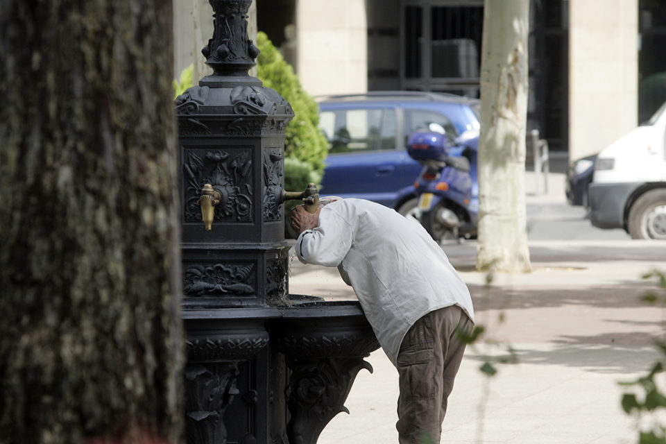 Un hombre bebe agua de una fuente. / Ingrid