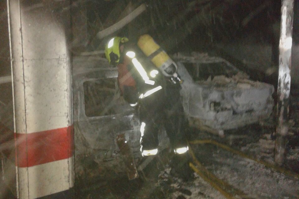 Un bombero trabaja en el garaje en el que han quedado dos coches calcinados. / NR