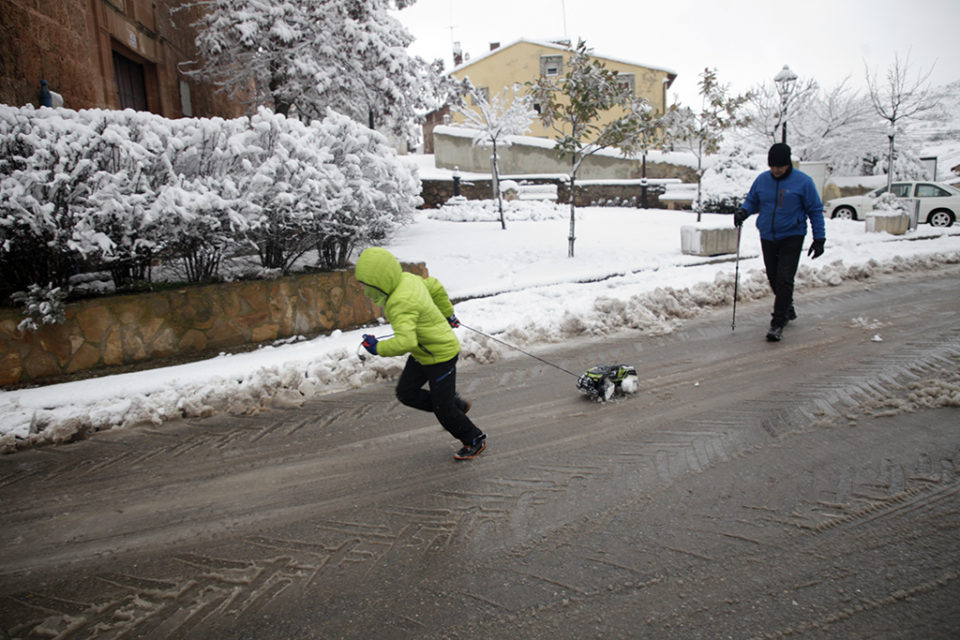 Un niño se divierte arrastrando un juguete por nieve en una calle de Clavijo. / Clara Larrea