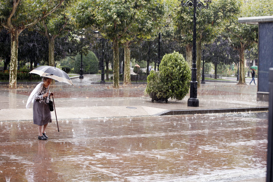 Una mujer se protege bajo su paraguas de la fuerte tormenta. / Clara Larrea