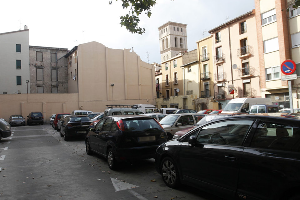 Aparcamiento situado en el barrio de La Villanueva, con la torre de San Bartolomé al fondo. / Clara Larrea
