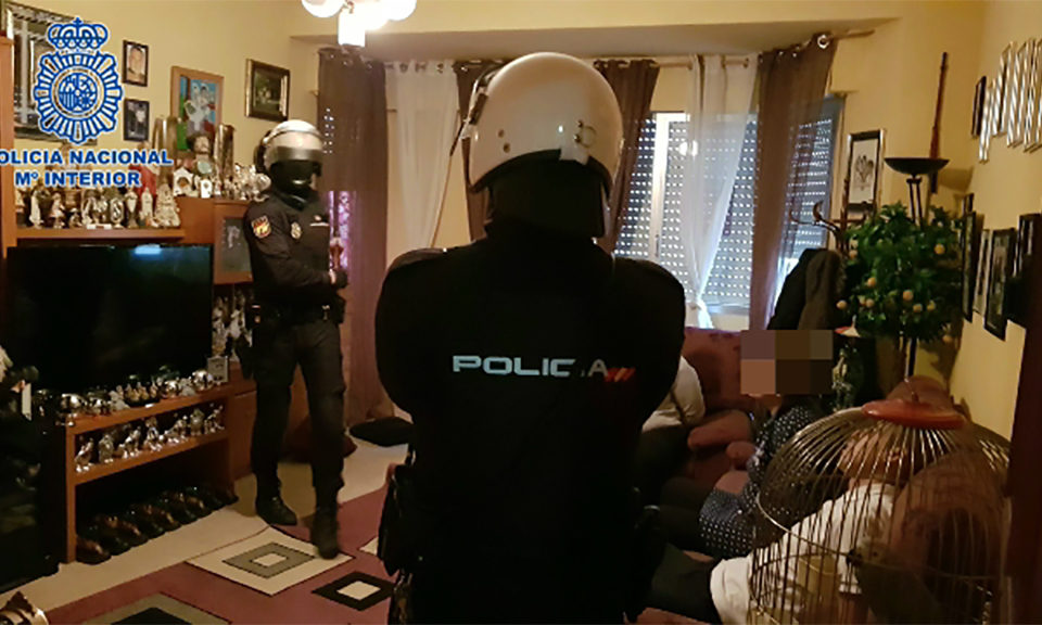 Los agentes, con los detenidos, en el momento del registro de la vivienda. / Policía Nacional
