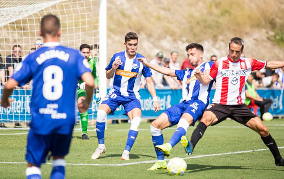 El vitoriano César Caneda pelea por el esférico con los jugadores del filial blanquiazul. / Deportivo Alavés