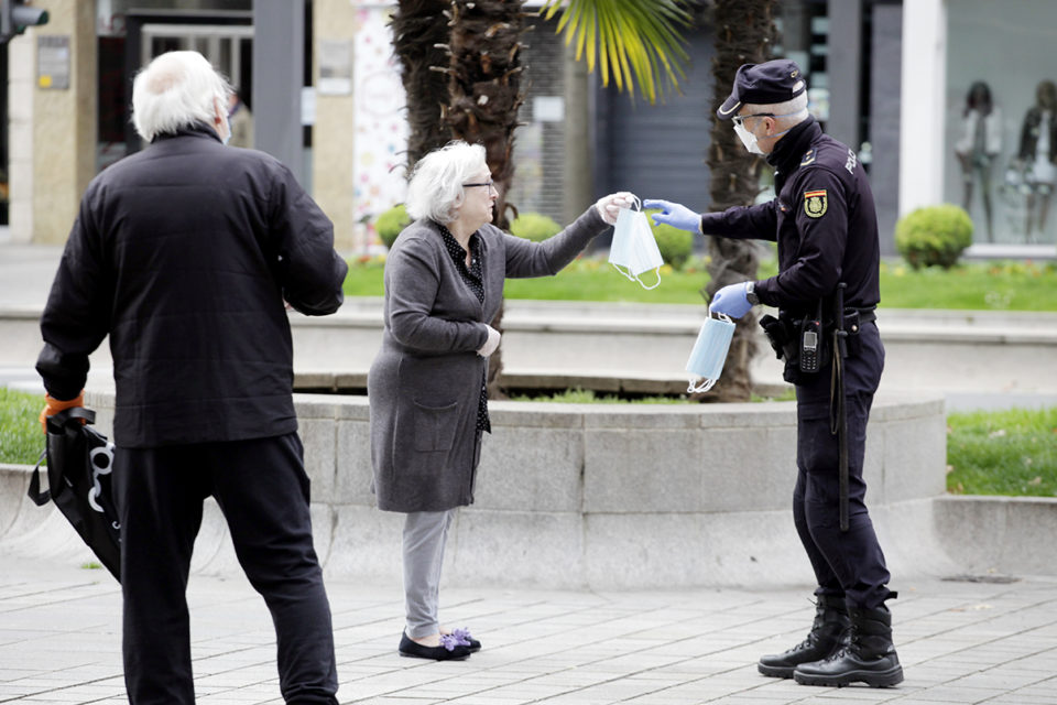 Un policía nacional entrega una mascarilla a una ciudadana en Gran Vía. / Ingrid